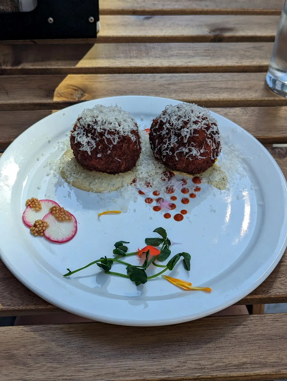 Two crisp fried croquettes under a blizzard of grated parmesan with pickled mustard seed and pea shoots