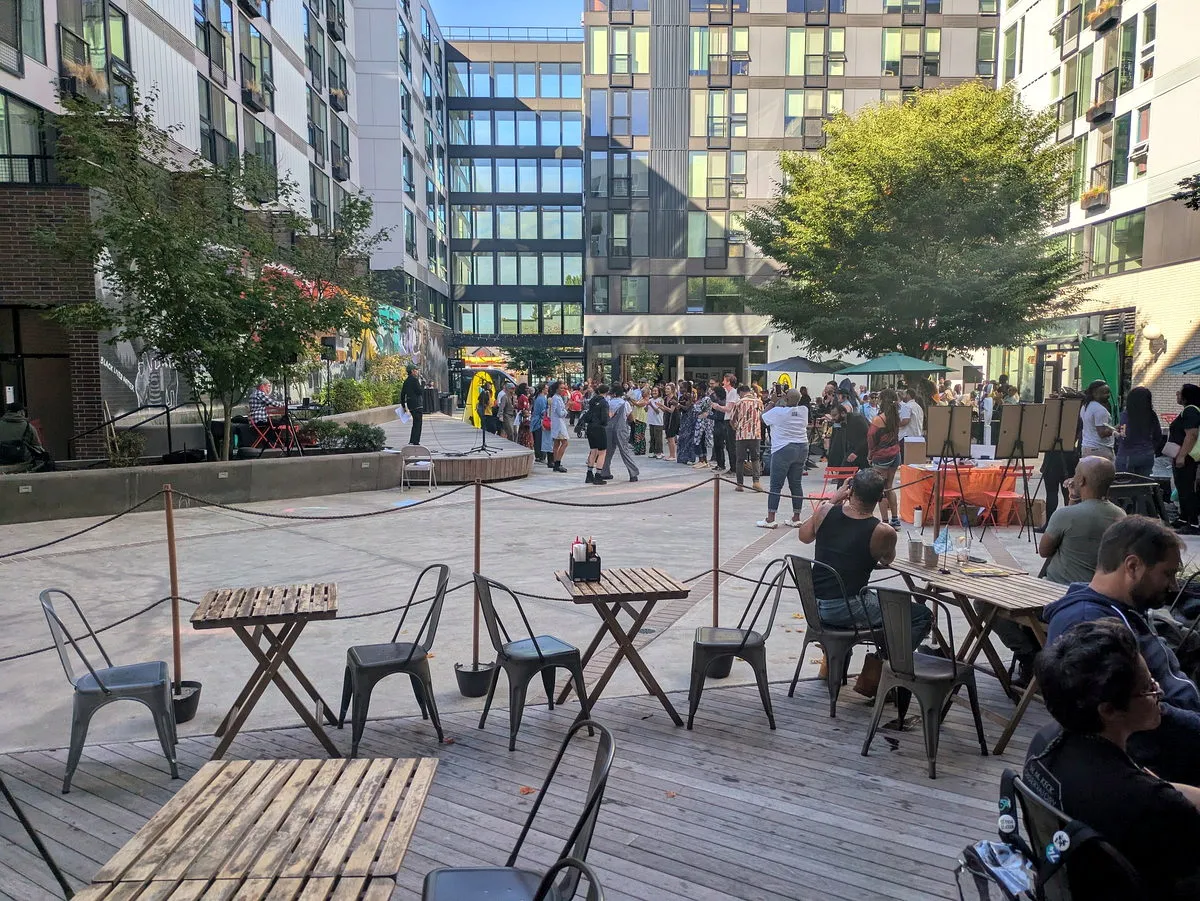 The Midtown Square plaza filled with neighbors on an evening, tables in the foreground